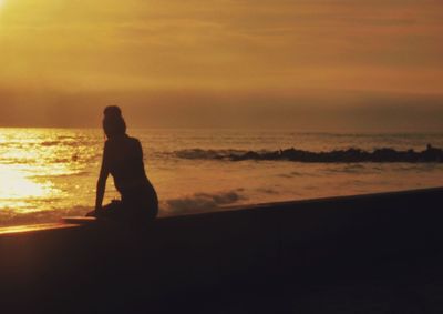 Silhouette woman standing at beach during sunset