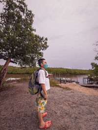 Young boy standing at the wooden jetty waiting for the boat in merang, terengganu.