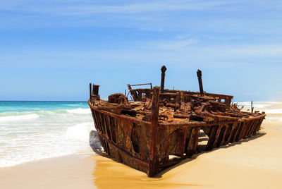 Abandoned boat on sea shore against sky