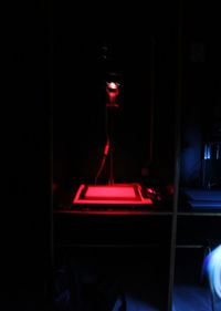 Illuminated electric lamp on table in darkroom