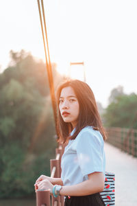 Side view of beautiful young woman drinking against blurred background