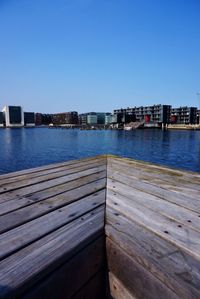 Pier in front of sea against clear blue sky