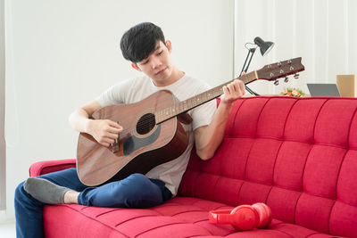 Man playing guitar on sofa