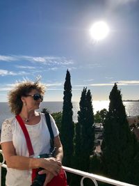 Woman standing by tree against sky