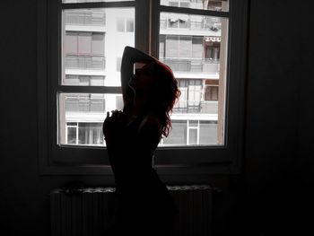 Side view of silhouette woman standing against window