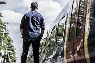 Rear view of man standing by train