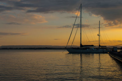 Sailboats in sea against sky during sunset