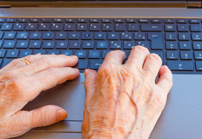 Cropped hands of senior woman using laptop