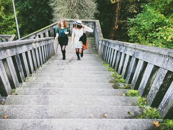 High angle view of young female friends talking while climbing steps