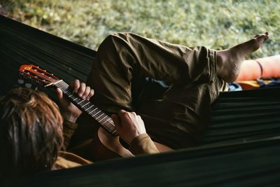 Man playing guitar while sitting in hammock