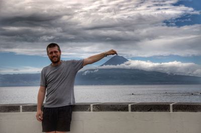 Optical illusion of man touching mountain peak against cloudy sky