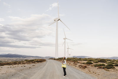 Engineer standing on dirt road by wind turbines at wind farm