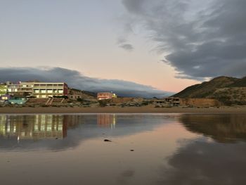 Buildings by lake against sky in city