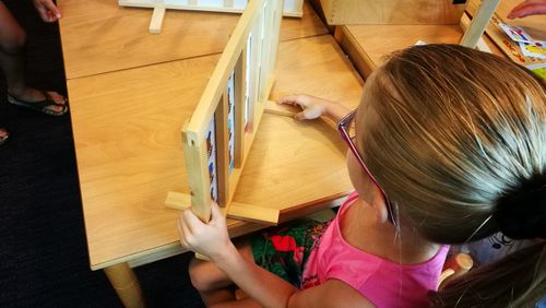 Girl reading wooden educational chart at table