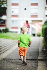 Rear view of boy walking on footpath