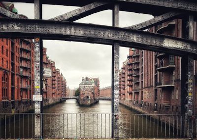 Bridge over river amidst buildings against sky