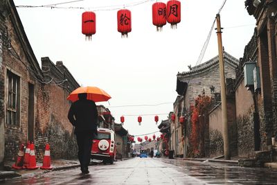 Rear view of man on street amidst buildings in city