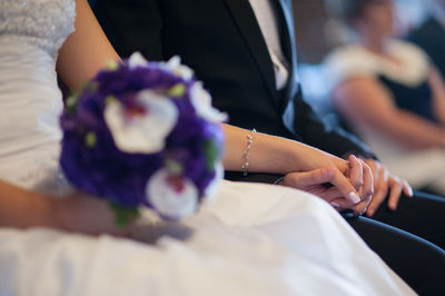 Midsection of bride and groom holding hands during wedding