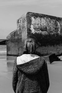 Rear view of woman standing against wall at beach