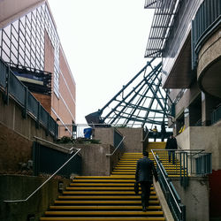 Rear view of businessman moving on staircase amidst buildings