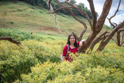 Portrait of smiling woman standing by plants and tree