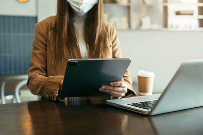 Midsection of woman using laptop on table