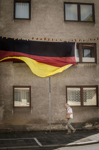 Senior woman walking against building with large german flag