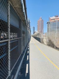 Chainlink fence against sky in city with bike lane over nyc bridge