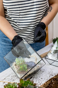 Midsection of woman holding flower standing on table