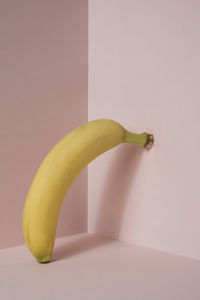 One banana against pink background.