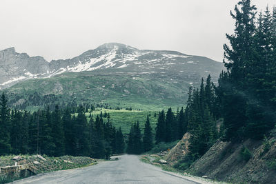 Road amidst trees and mountains against sky