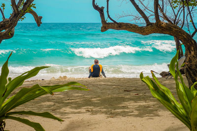 Rear view of men sitting at beach