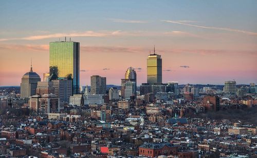 Modern buildings in city against sky during sunset