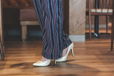 Low section of woman walking on wooden floor