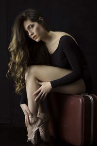 Portrait of beautiful woman sitting against black background