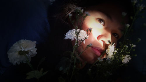 Close-up of woman by flowers at night