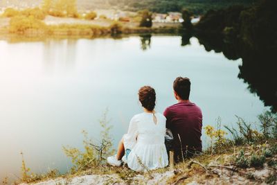 Rear view of couple sitting by lake