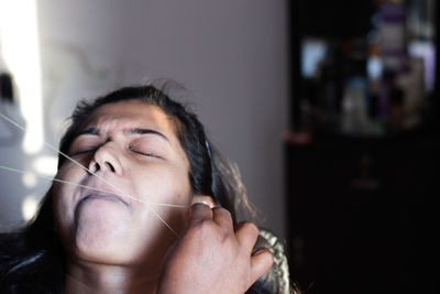 Cropped hands of beautician threading woman skin