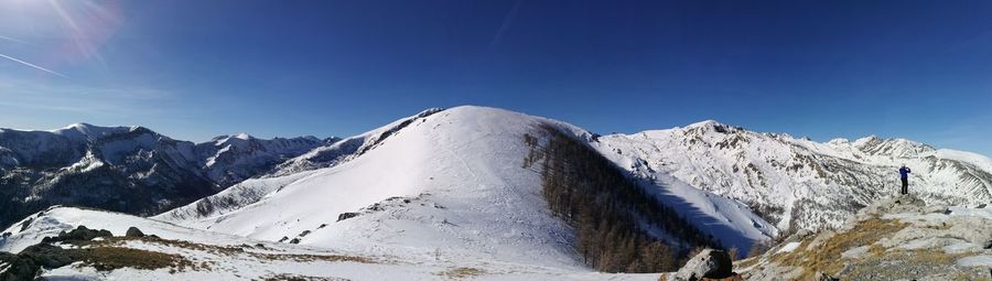 Panoramic view of snowcapped mountains against blue sky