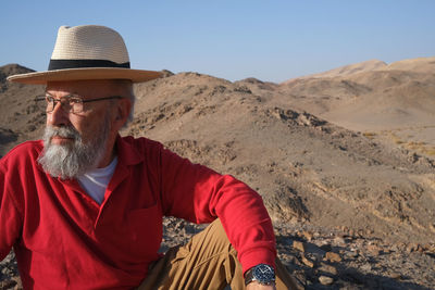 Senior man in red looking awy in the desert 