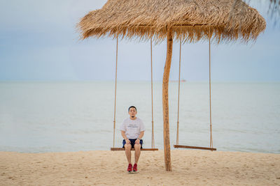 Full length of boy standing on beach against sky