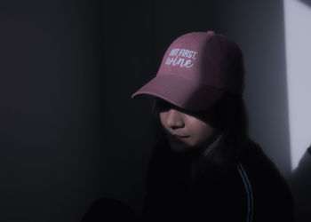 Portrait of woman wearing hat against black background