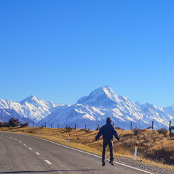 Rear view of man against snowcapped mountain and clear sky