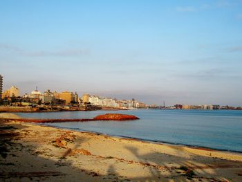Scenic view of sea by buildings against sky