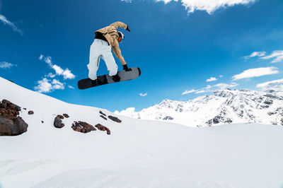 Low angle view of man skiing on snowcapped mountain against sky