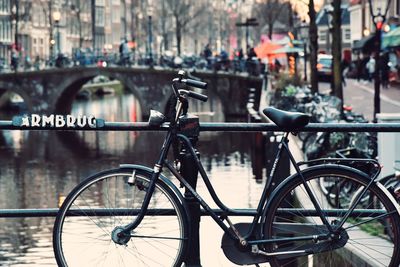 Bicycle parked on bridge over river in city