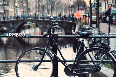 Bicycle parked on bridge over river in city