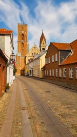 Footpath amidst buildings against sky in city