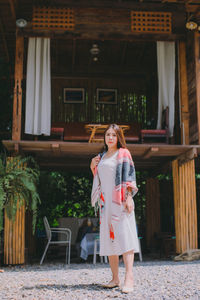 Full length portrait of smiling girl standing against built structure