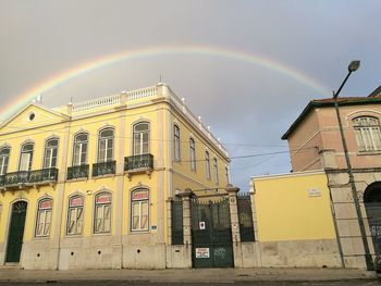 Low angle view of rainbow over building against sky